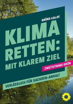Vor einem Baum und einem See steht das Banner mit der Aufschrift "Klima retten: Mit klarem Ziel – Verlässlich für Sachsen-Anhalt" und dem Hinweis "Zweitstimme Grün"
